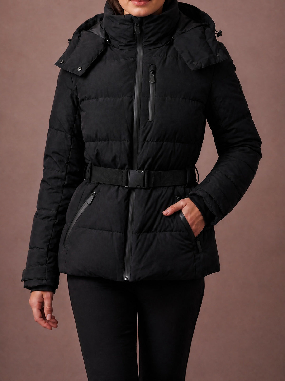 Woman walking in the black belted winter jacket, hand in the side pocket, studio view