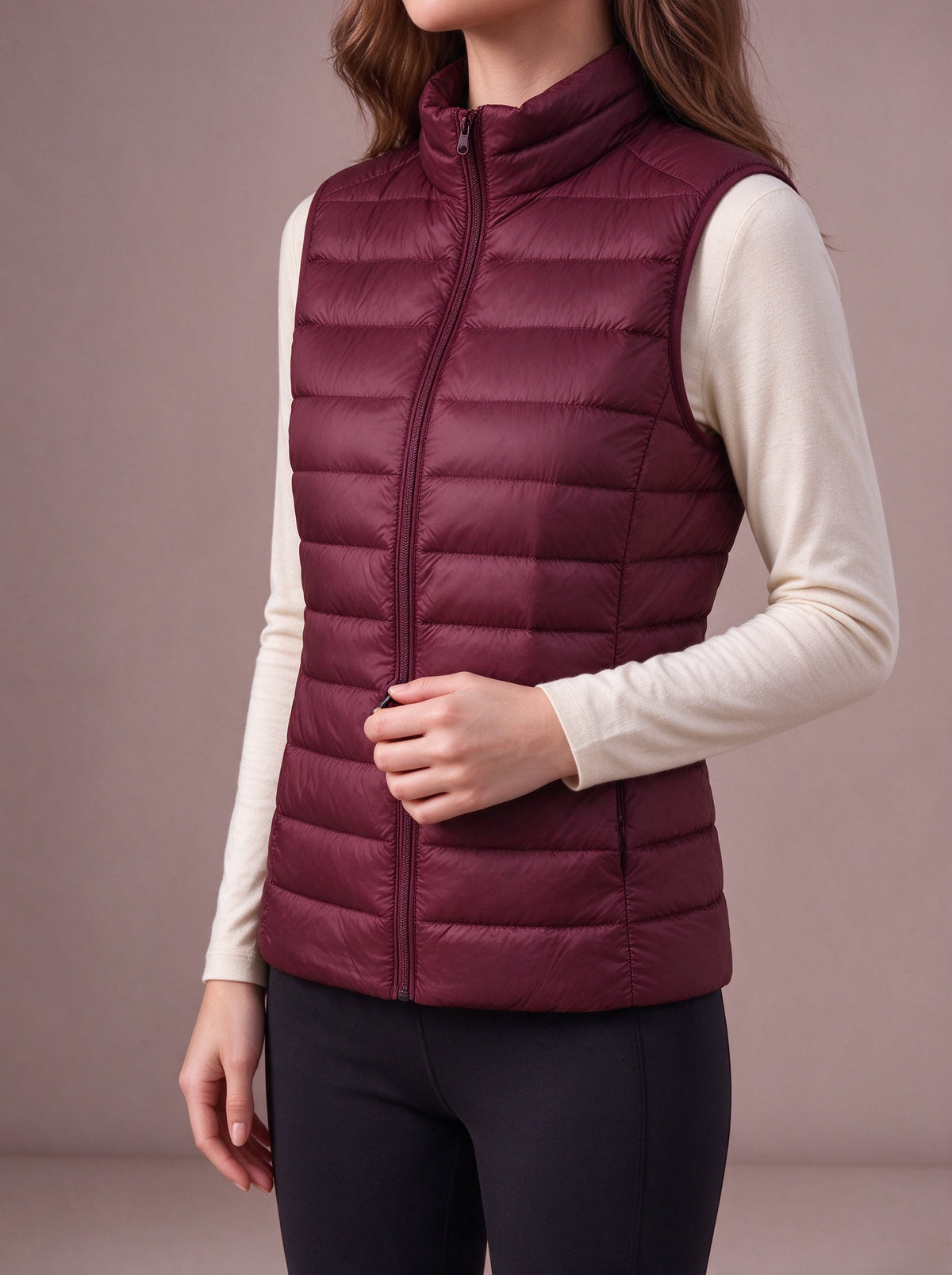 Burgundy packable down vest over a cream top, studio view