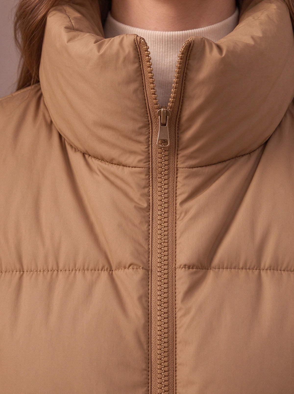 Tall stand-up collar and zip of the camel quilted vest, close view