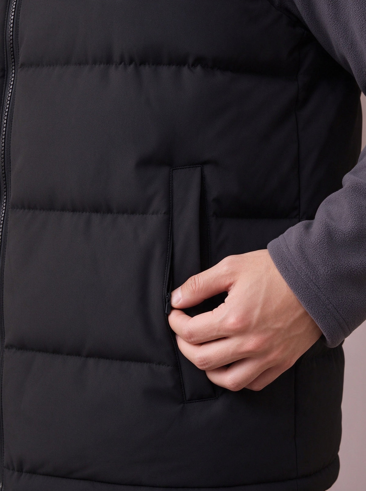 Zipped hand pocket and wide quilting of the black quilted vest, close view