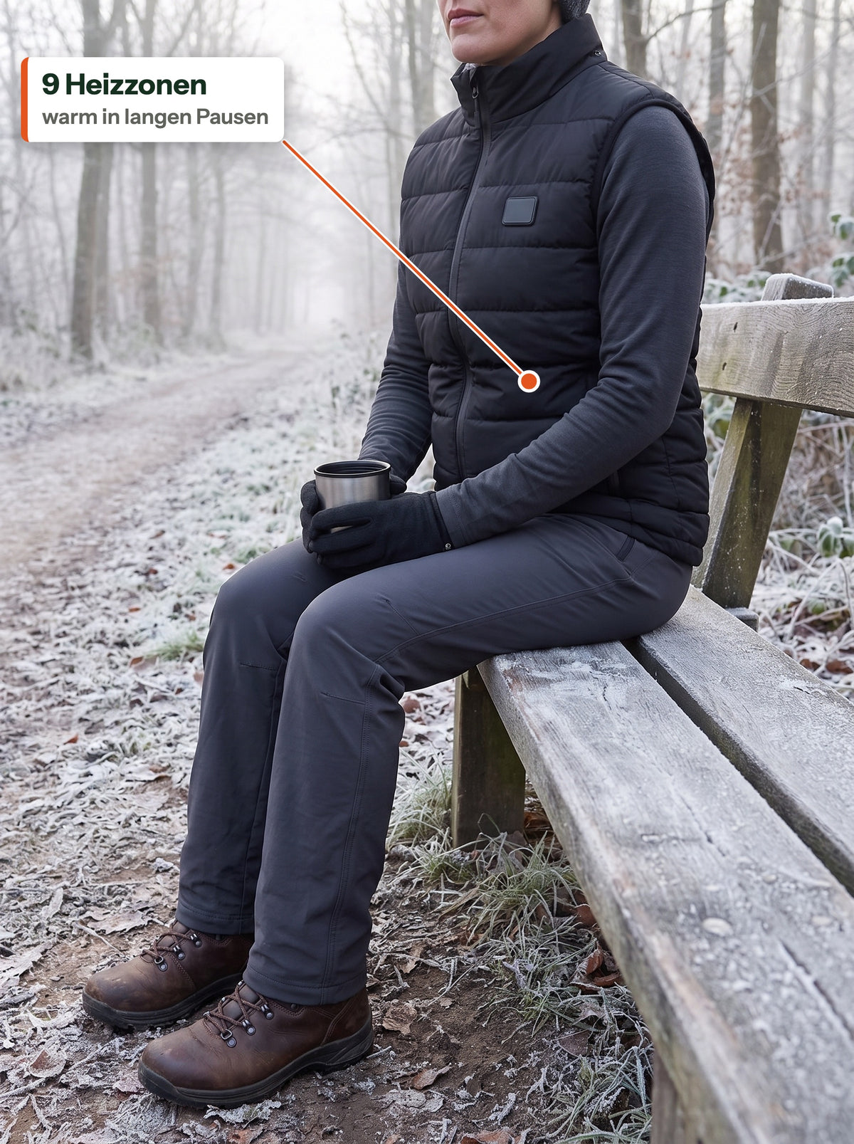 Frau in der schwarzen HeatCore Bodywarmer auf einer Bank am frostigen Wanderweg mit einem heißen Getränk: 9 Heizzonen, warm in langen Pausen
