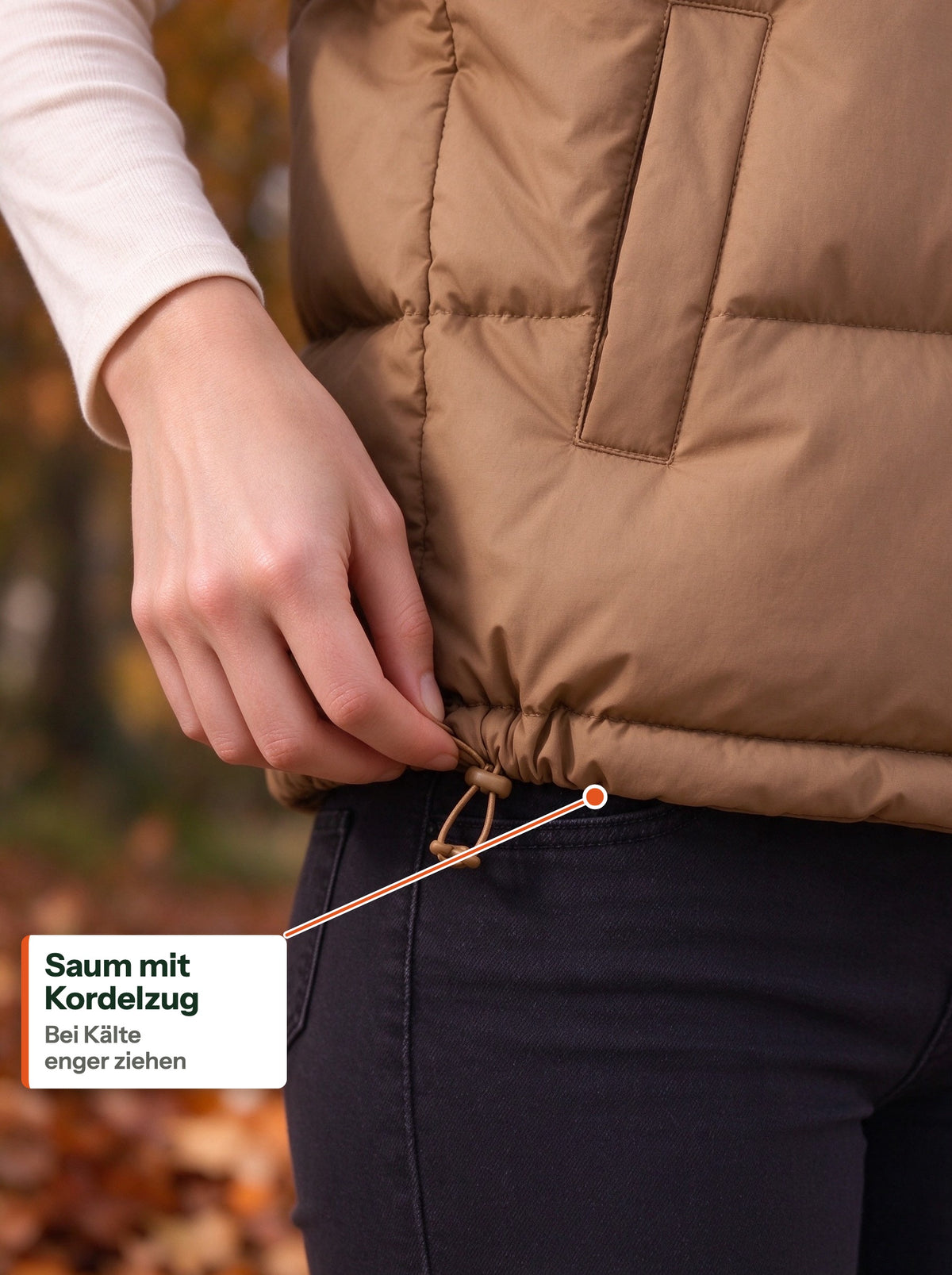 Hand pulling the drawcord toggle at the hem of the camel quilted vest (DE Label)