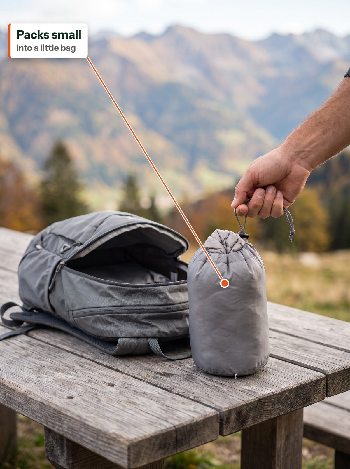 Down jacket packed into a small stuff bag next to a daypack (EN label)