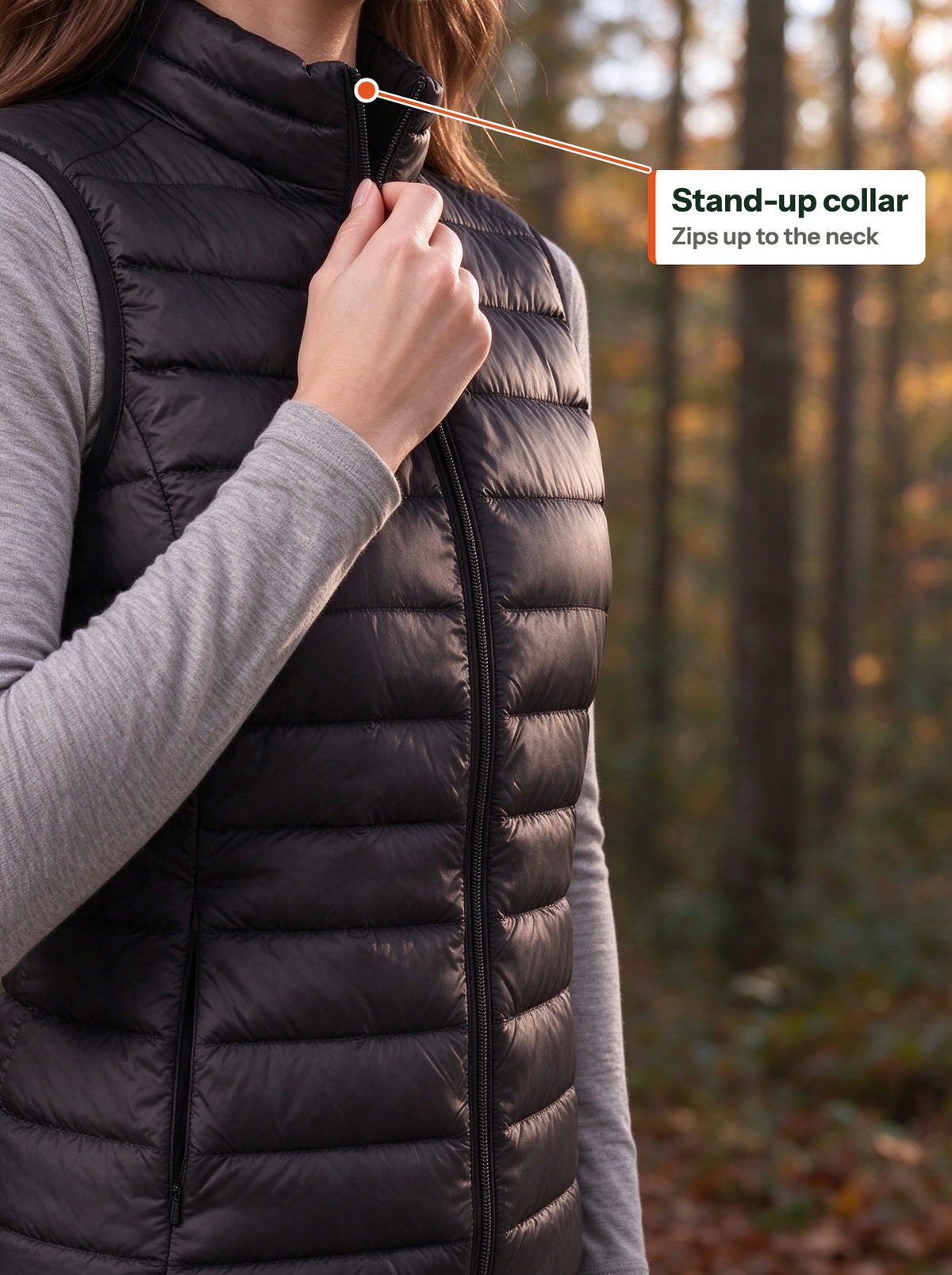 Hand zipping the low stand-up collar of the black down vest (EN label)