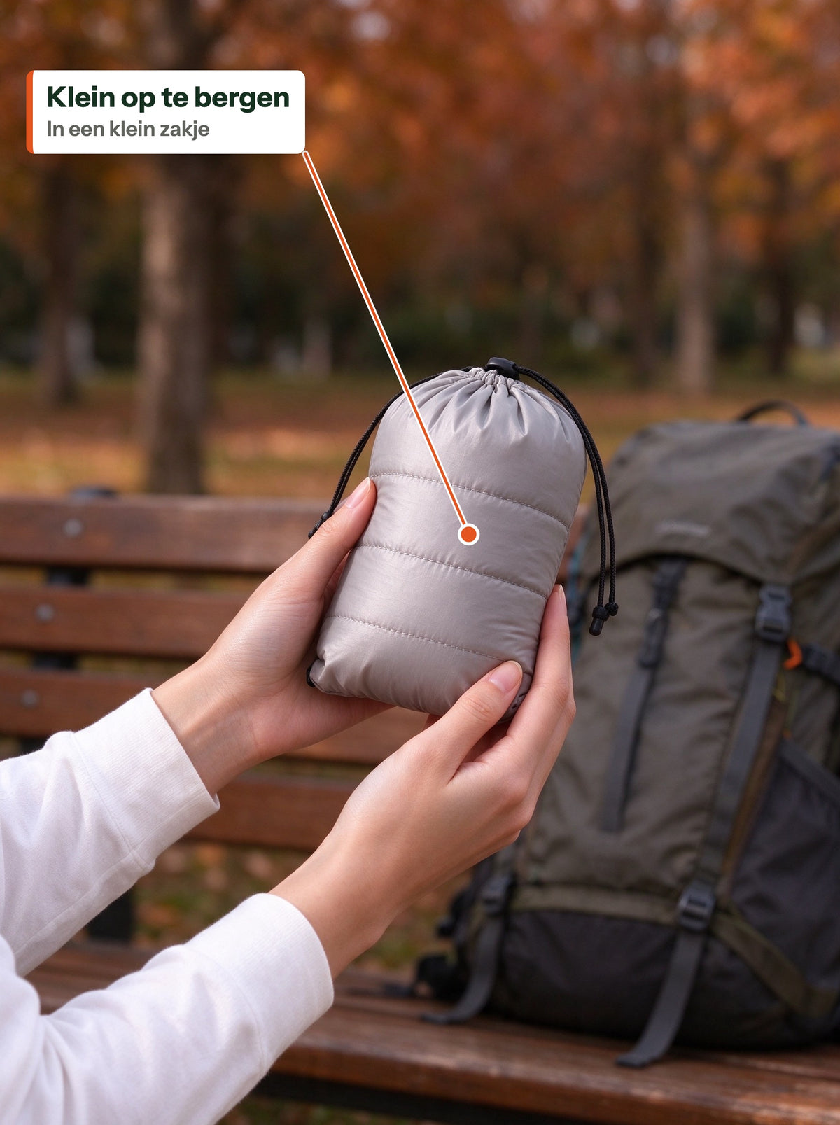 Light down jacket packed into a small stuff bag, held in two hands (NL label)