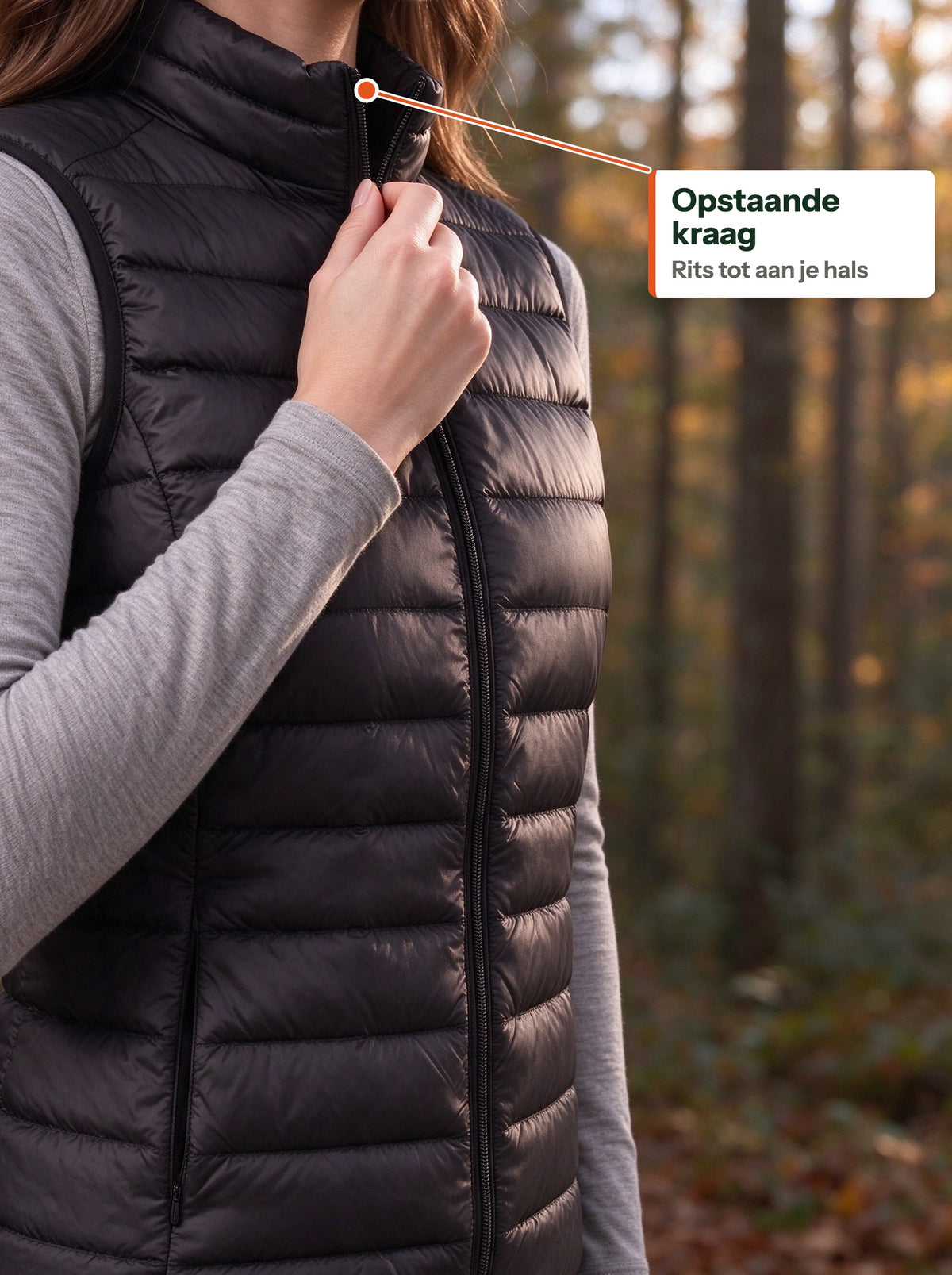 Hand zipping the low stand-up collar of the black down vest (NL label)