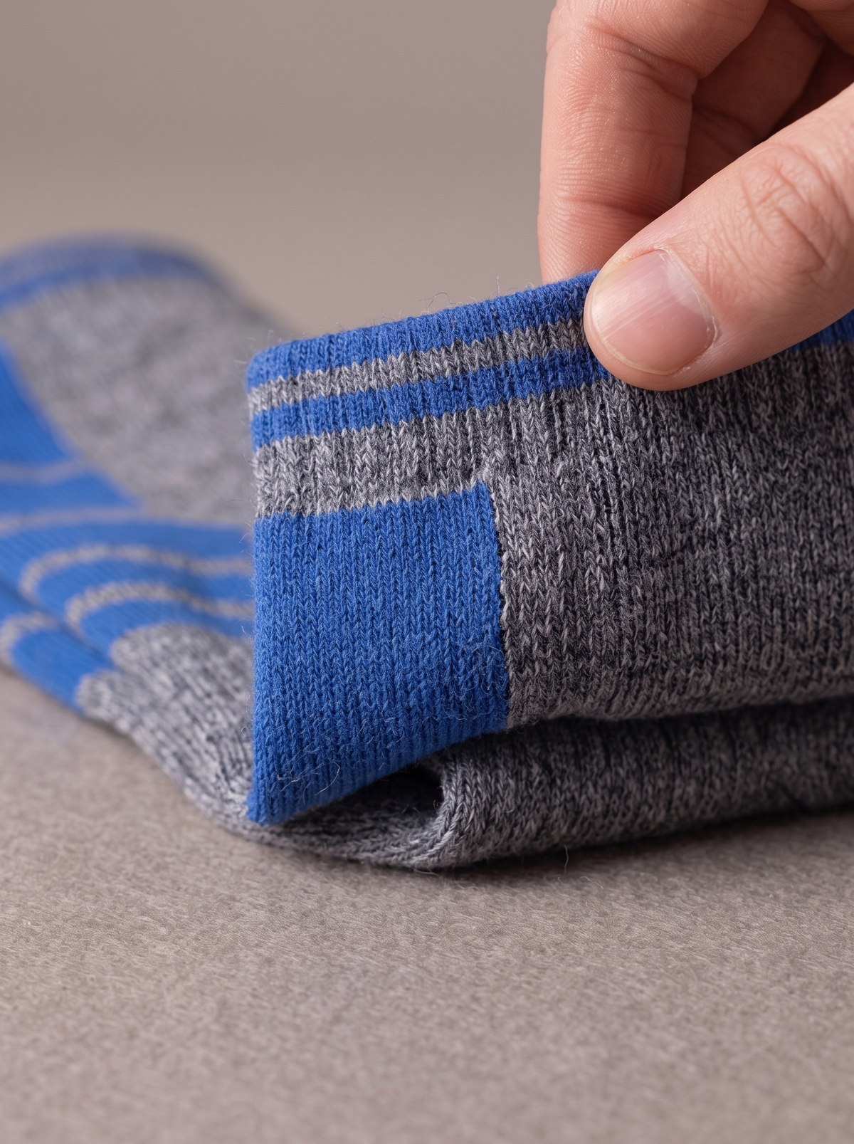 Heathered grey ski-weight knit sock with cobalt blue stripes, the folded cuff showing the knitted loops