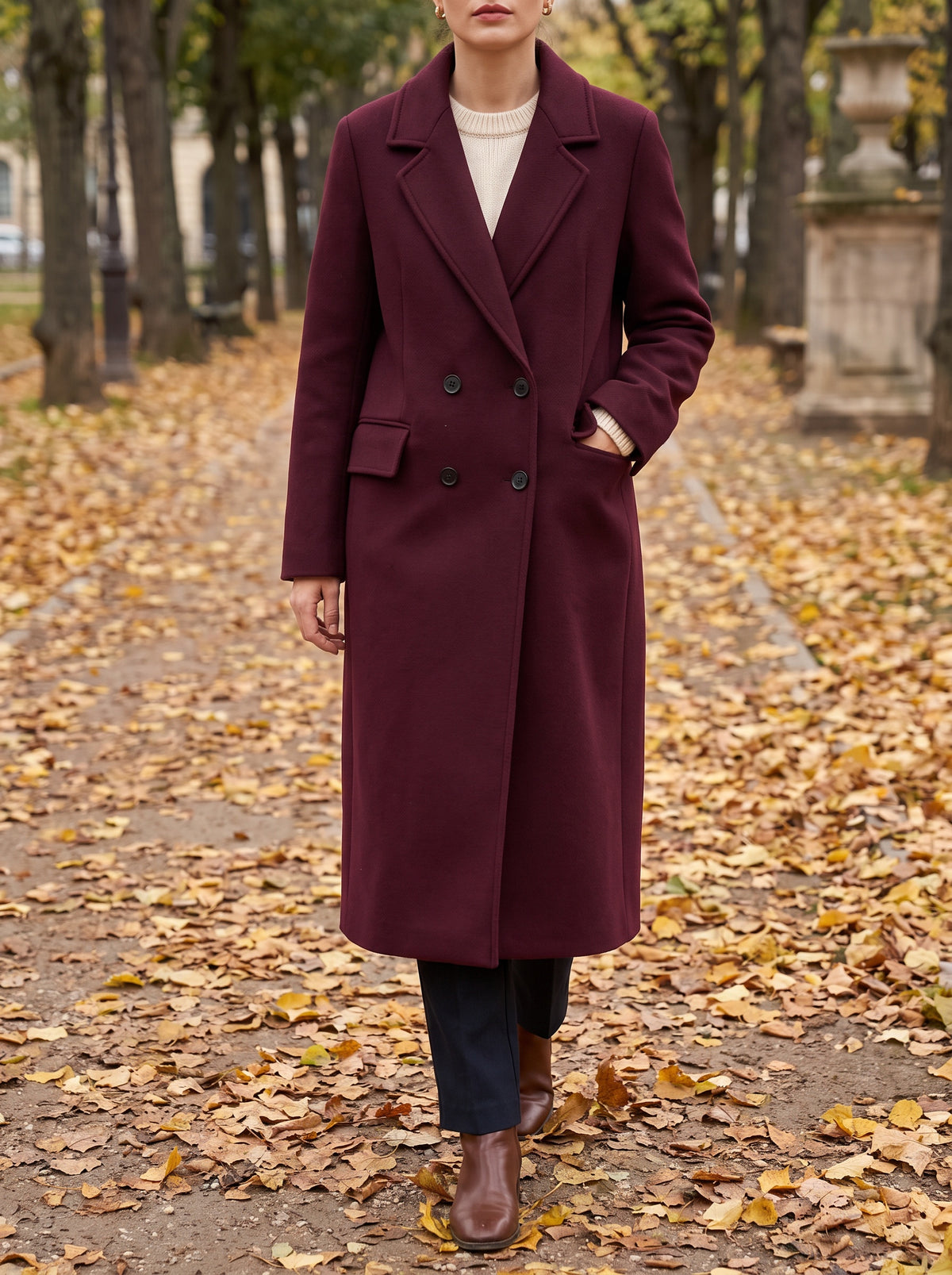 Woman walking a leaf-covered park path in the wine red long double-breasted coat
