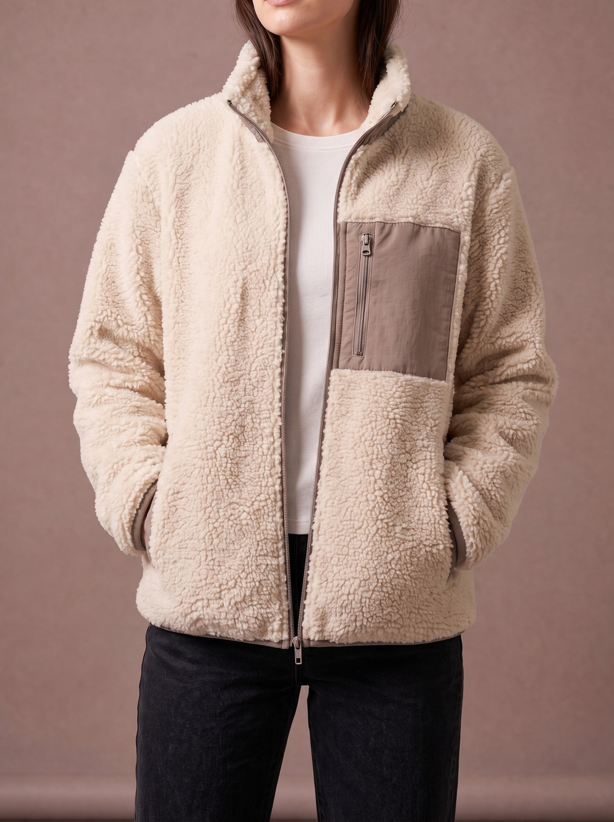 Beige teddy fleece jacket worn half open, hands in the side pockets, studio view