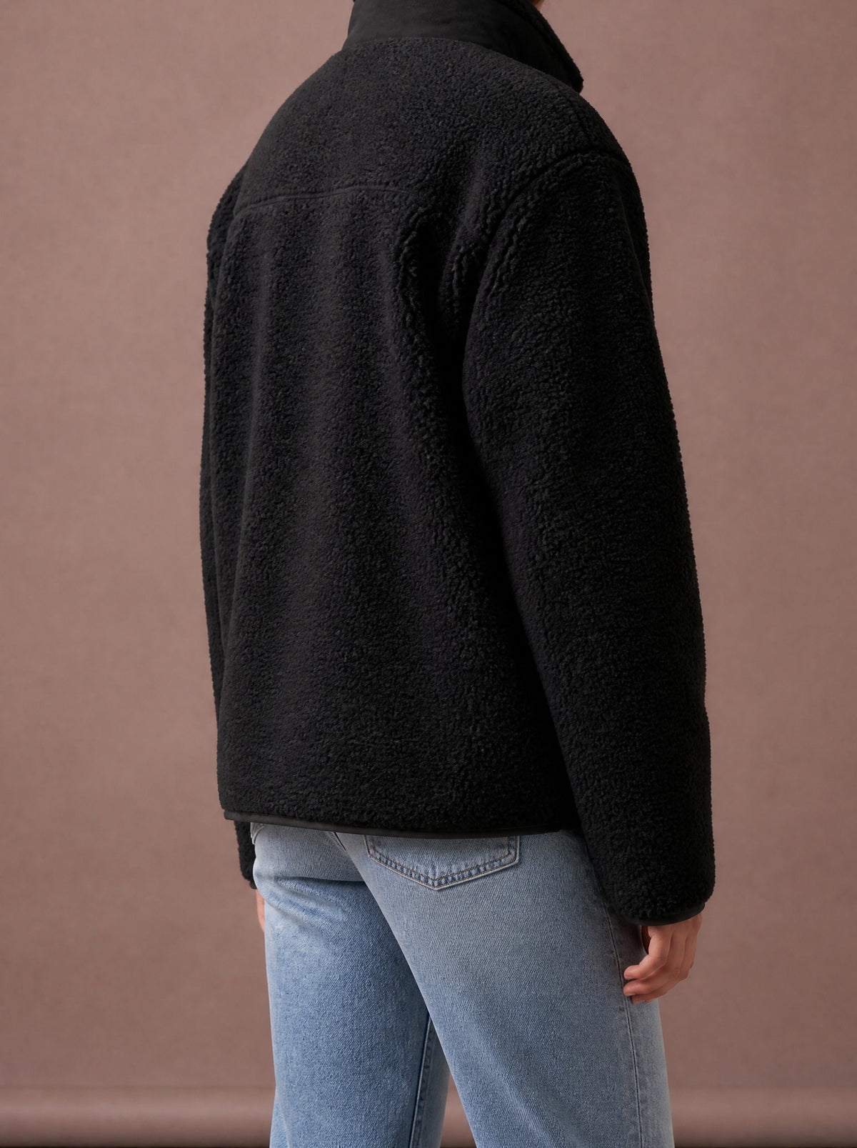 Black teddy fleece jacket from the back and side, studio view