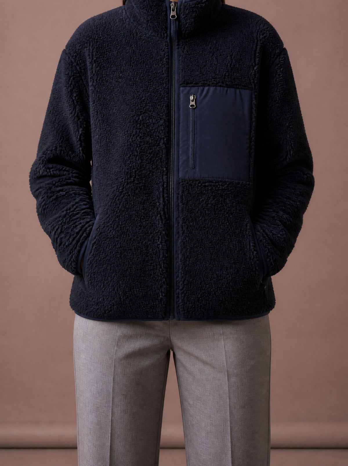 Navy teddy fleece jacket for women zipped up, hands in the side pockets, studio view