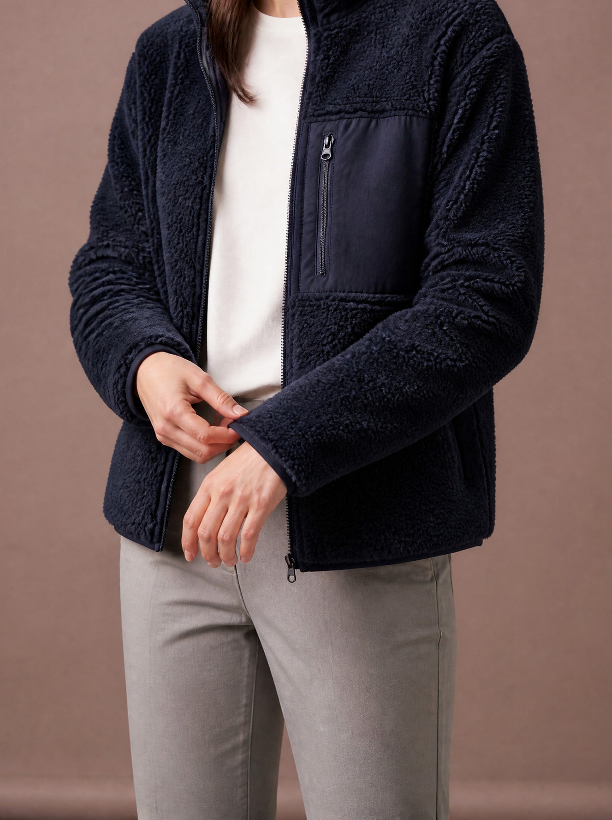 Navy teddy fleece jacket worn open over a white top, studio view