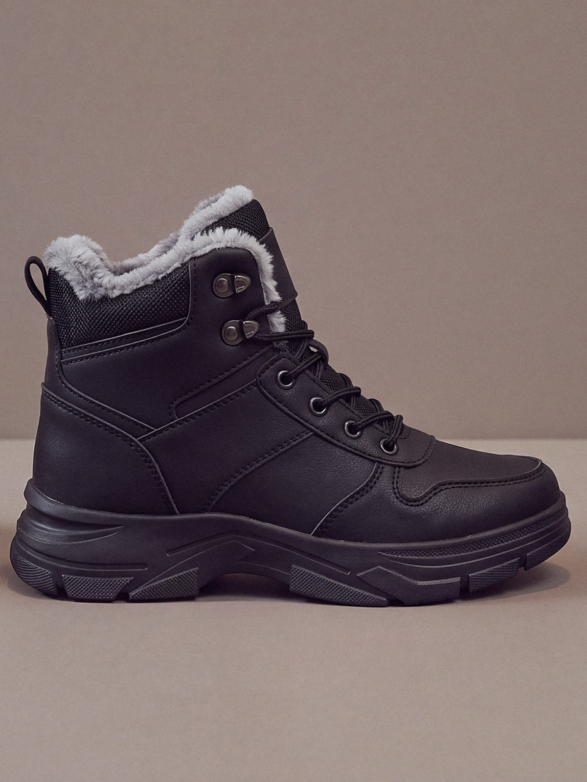 The Winter Trail Boot in black with a black sole, studio