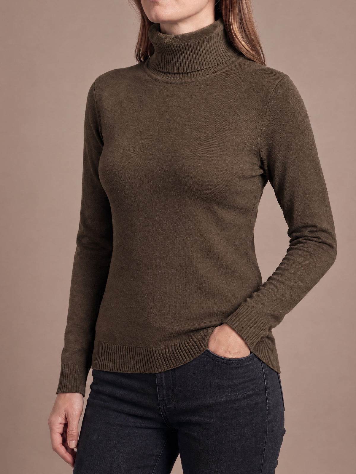 Woman wearing the plush-lined knit turtleneck in coffee brown with a hand in the jeans pocket, fold-over collar, slim fit and ribbed cuffs and hem