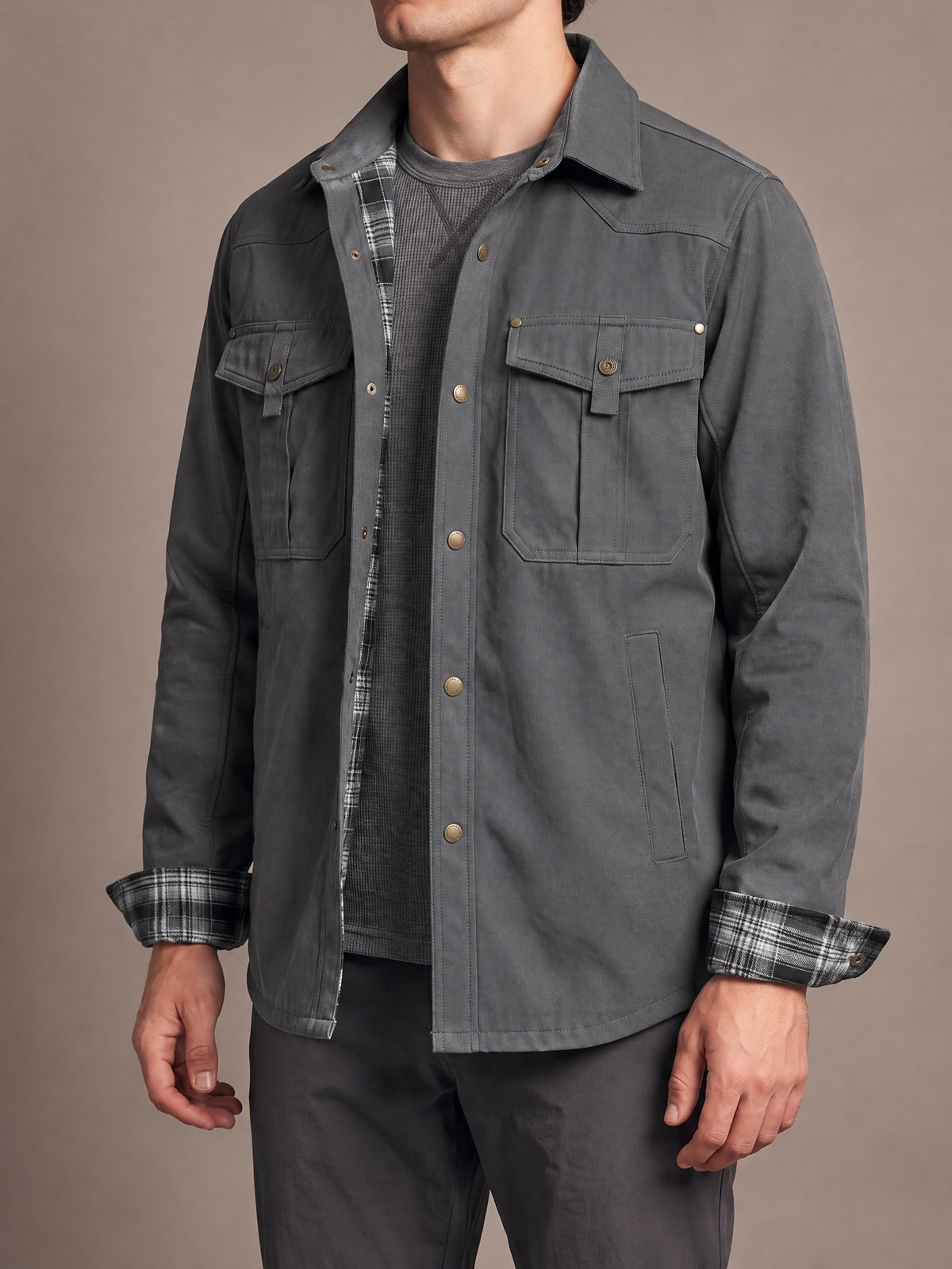 Flannel-lined shirt jacket in grey with grey and white plaid lining and cuffs, worn open, body turned slightly
