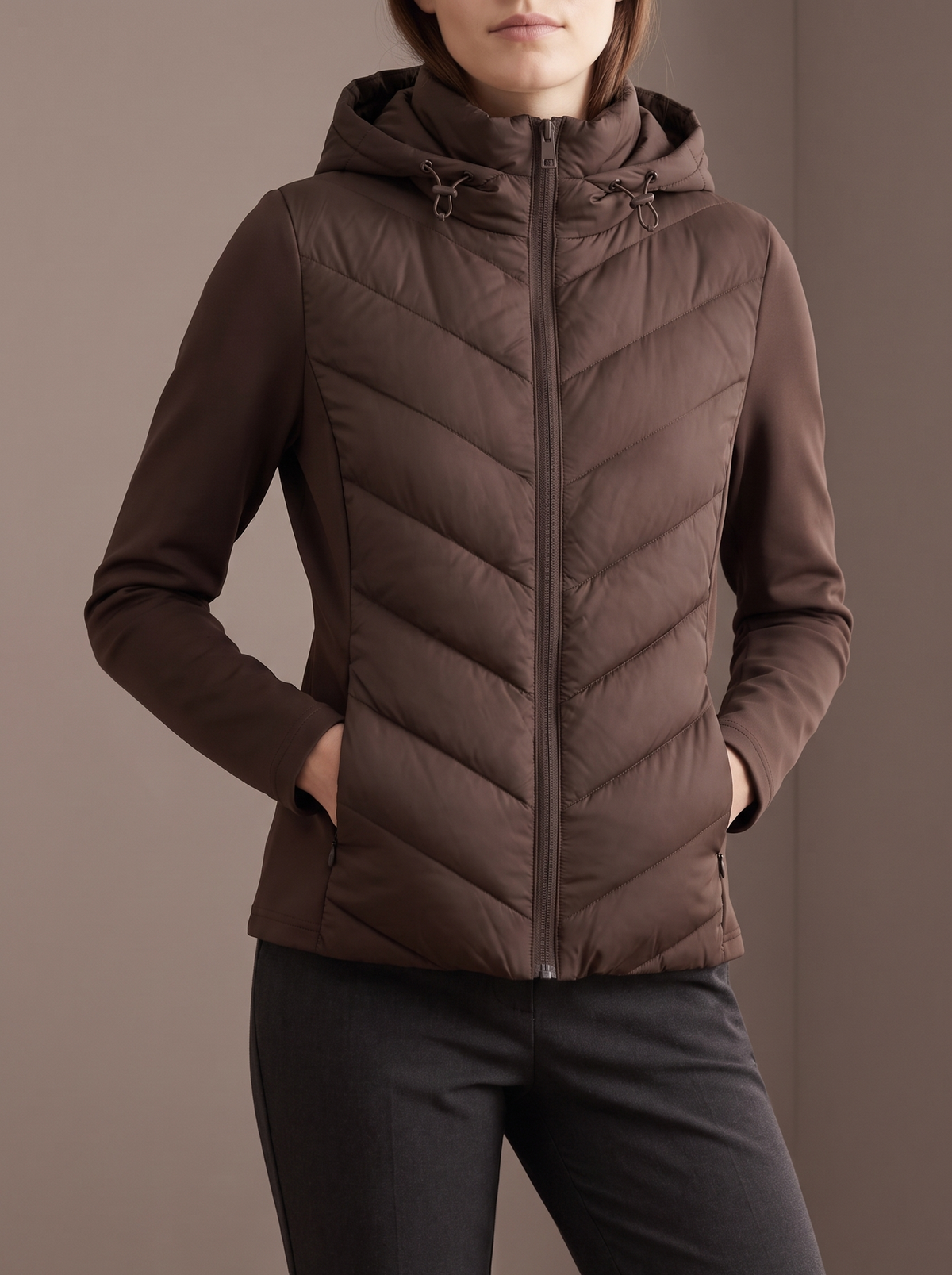 Women's brown chevron hybrid jacket worn with hands in the pockets, studio view