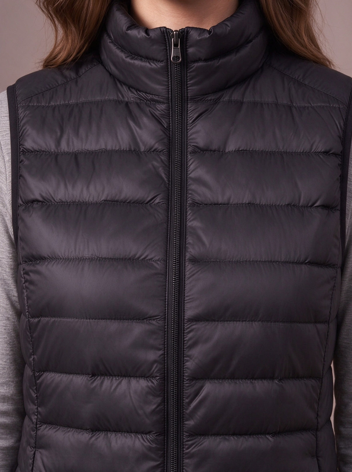 Low stand-up collar, zip and narrow quilting of the black down vest, close view