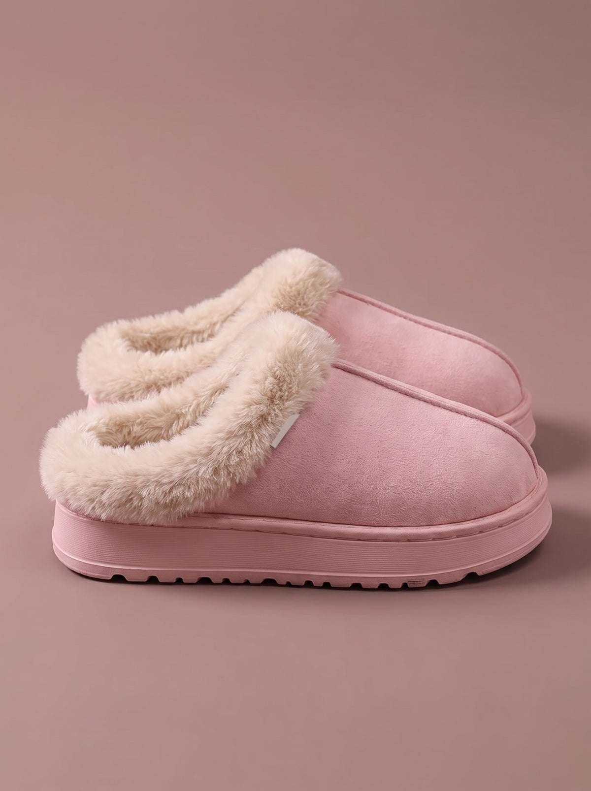 Ein Paar rosa Hausschuhe mit cremefarbenem Plüschrand, von der Seite