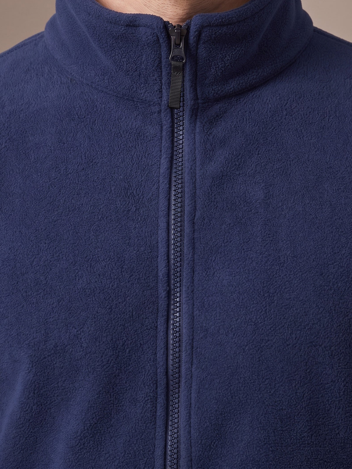 Close-up of the stand collar and front zip of the navy polar fleece jacket