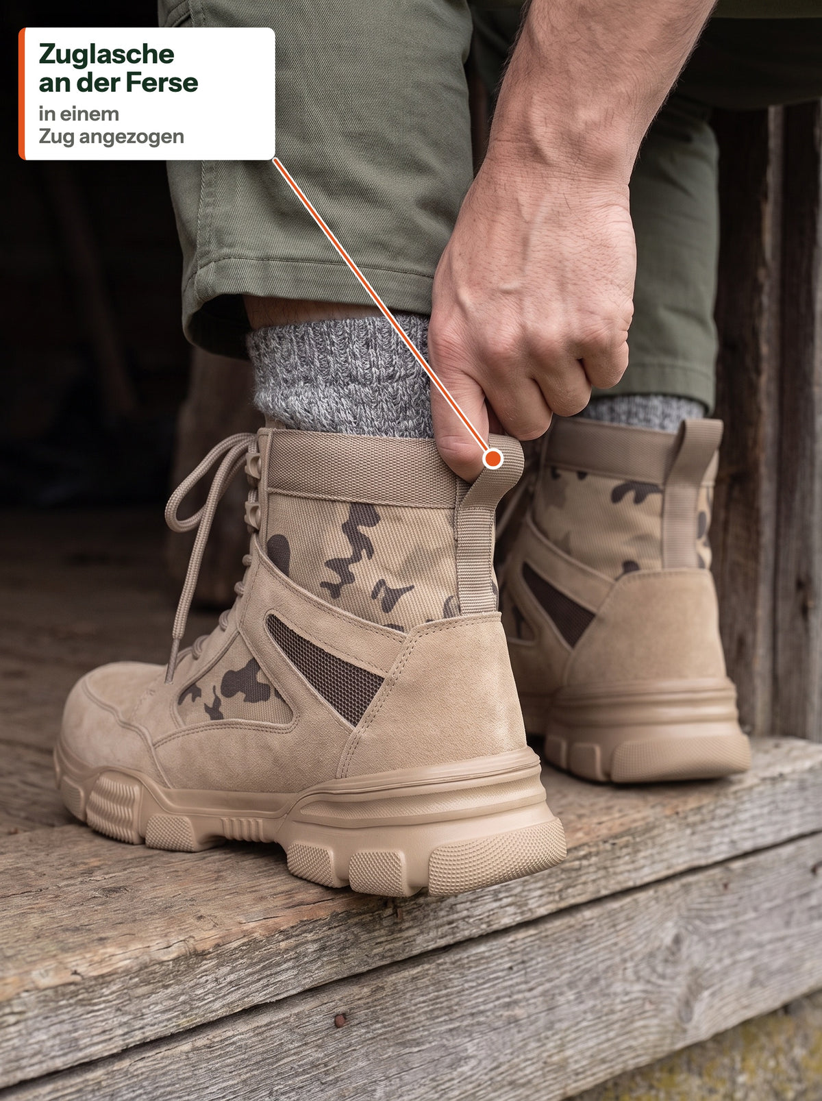 Hand zieht The Camo Work Boot an der Zuglasche an der Ferse an, auf einer Scheunenschwelle (DE Label)