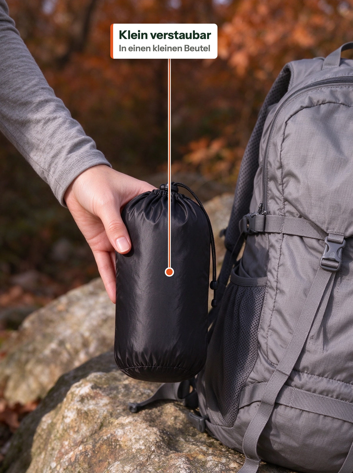 Down vest packed into a small black stuff bag next to a backpack (DE Label)