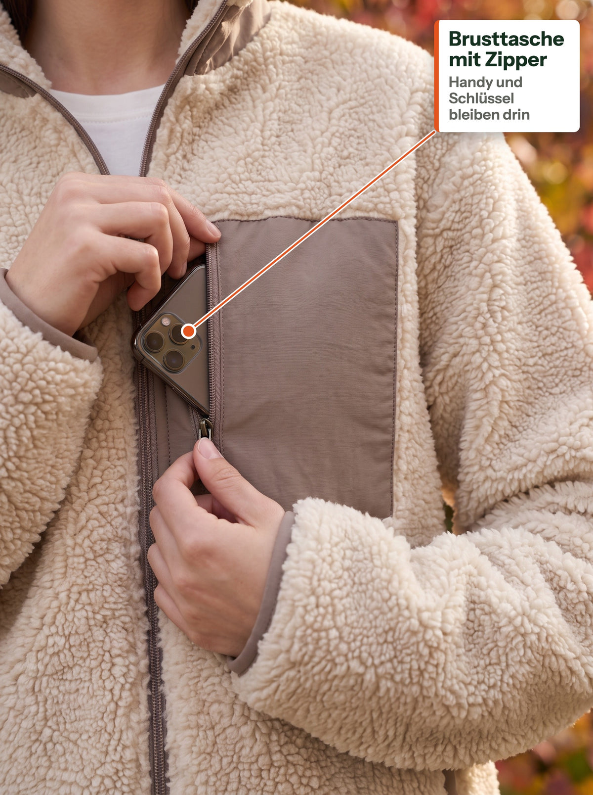 Handy in der gewebten Brusttasche mit Reißverschluss der beigen Teddyjacke (DE label)
