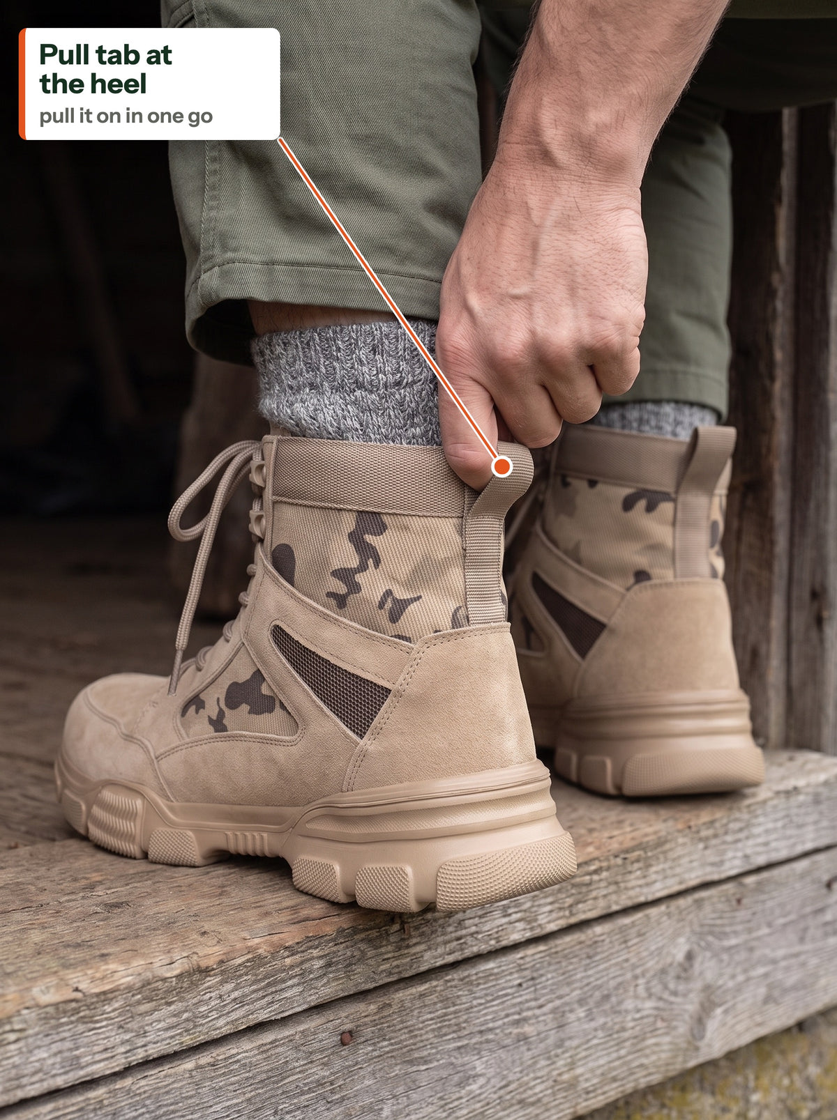 Hand pulling The Camo Work Boot on by the pull tab at the heel, on a barn doorstep (EN label)