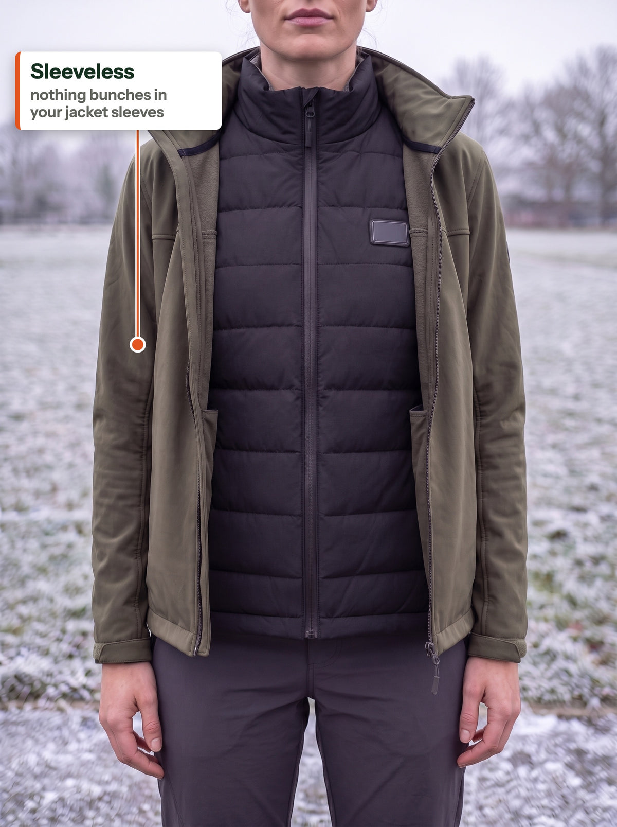 Black heated bodywarmer worn under an open olive softshell jacket on a frosty field: sleeveless, nothing bunches in the jacket sleeves
