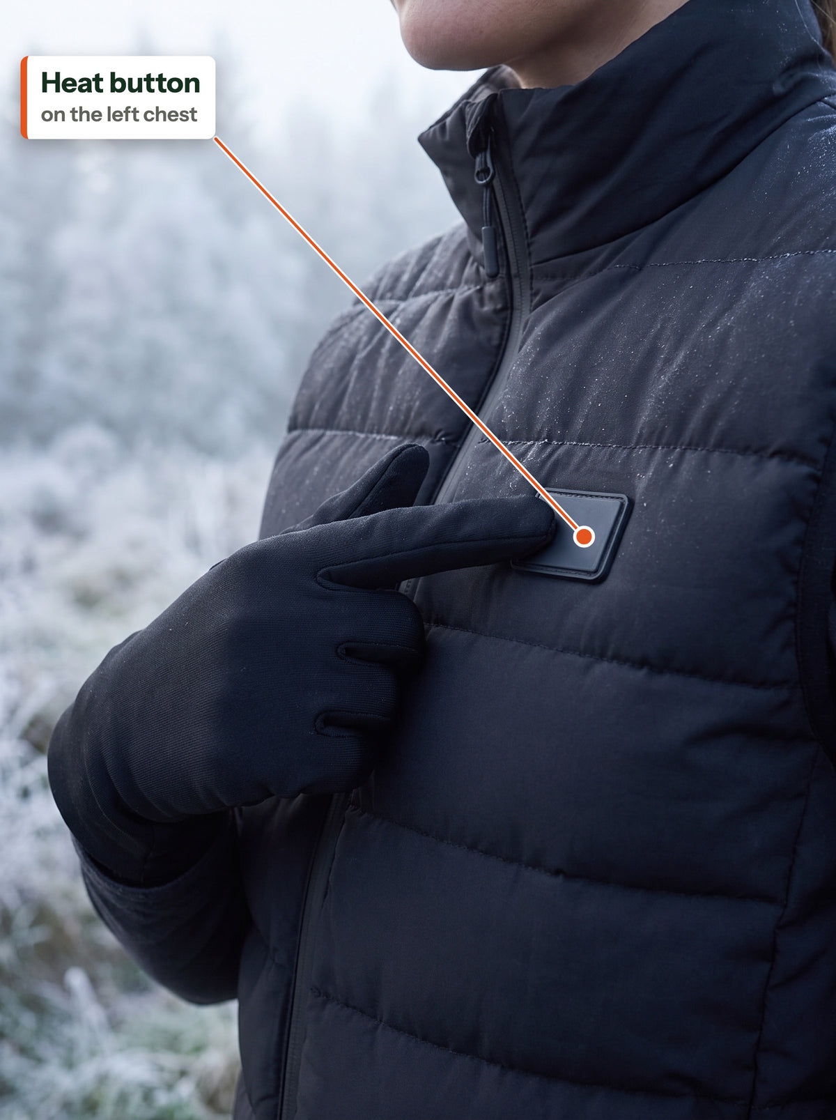 Gloved finger presses the heat button on the left chest of the black bodywarmer
