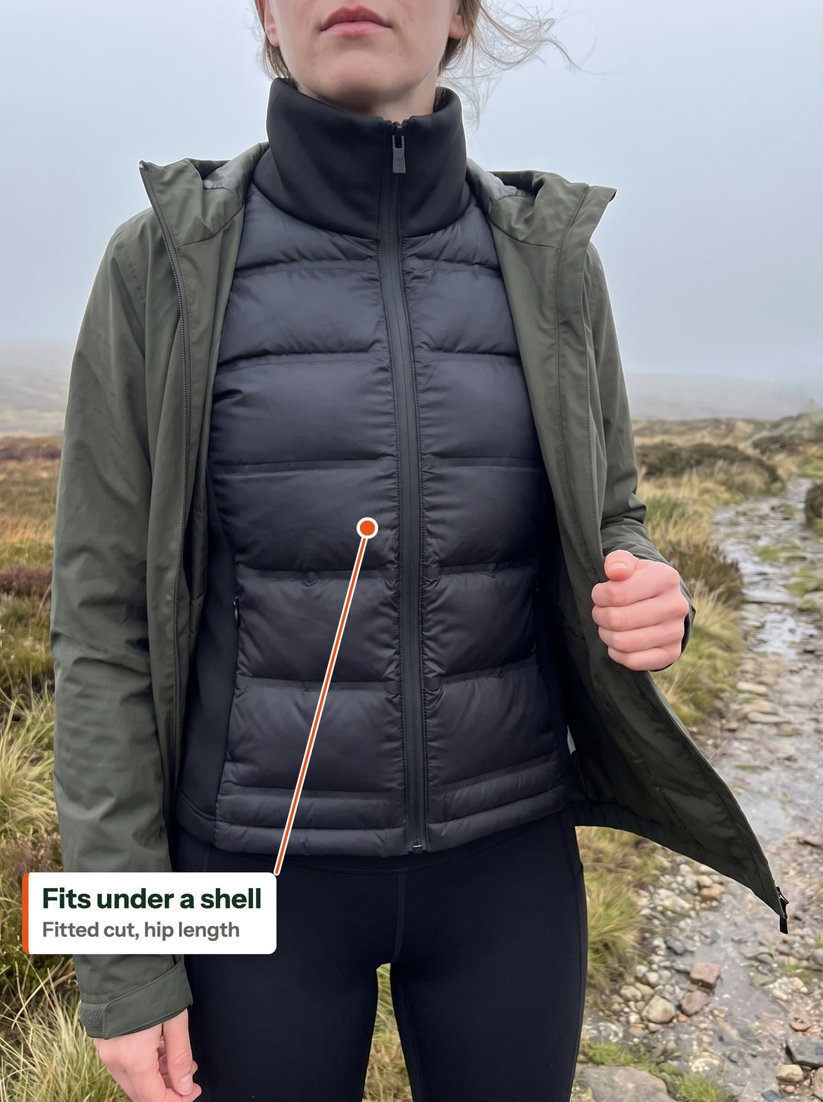 Hybrid puffer jacket worn under an open rain shell on a moor path (EN label)