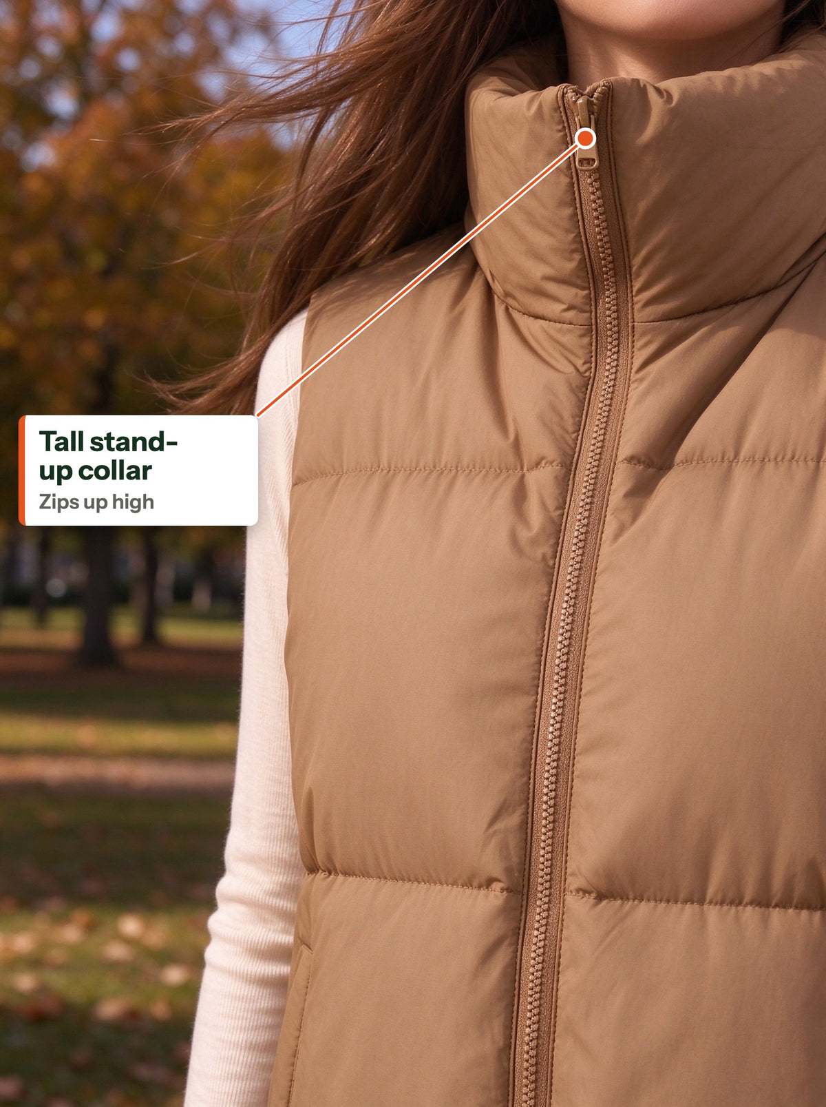 Tall stand-up collar of the camel quilted vest zipped up in a windy park (EN label)
