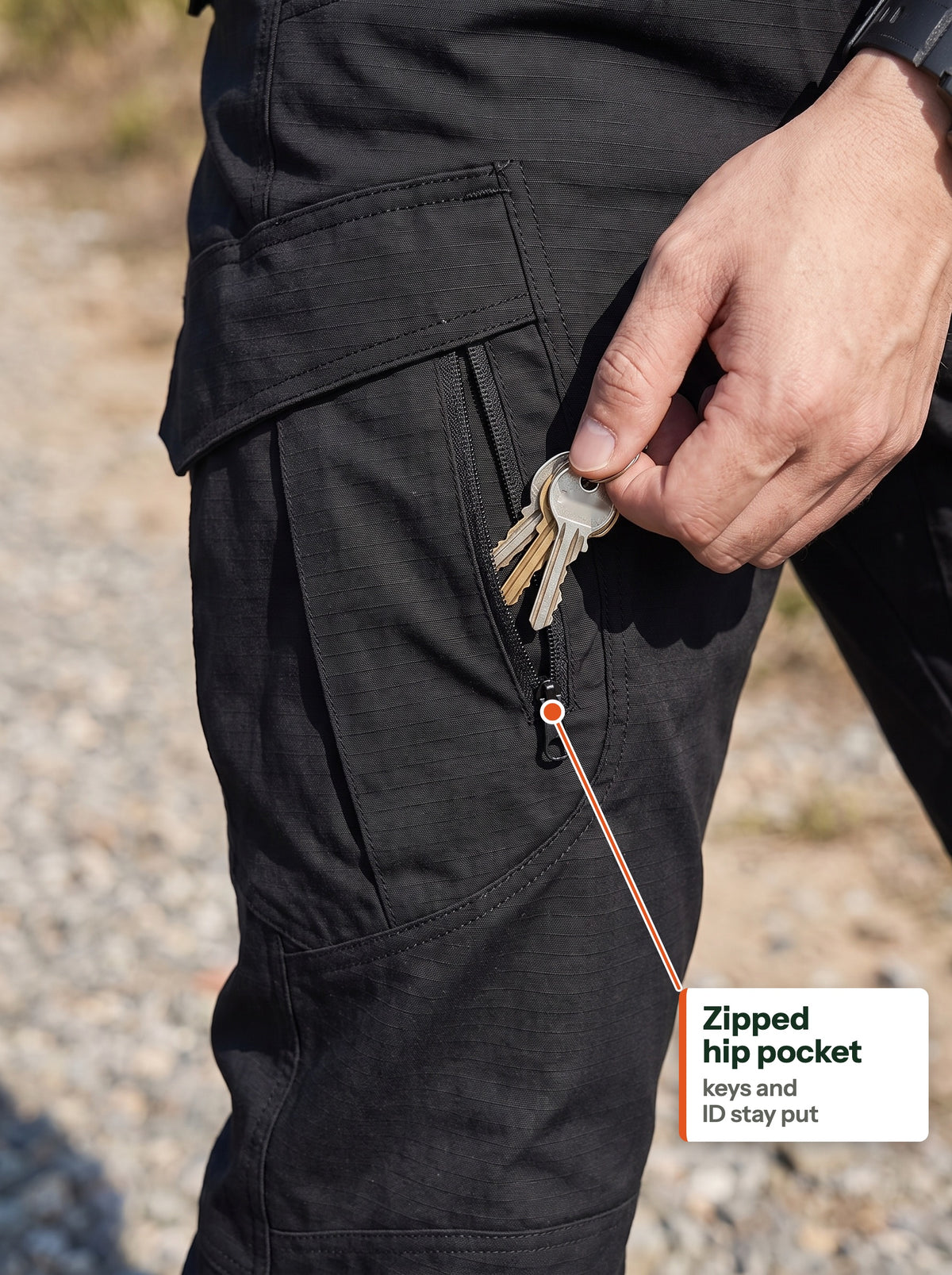 Keys going into the zipped hip pocket of the black tactical cargo trousers, flapped cargo pocket above (EN label)