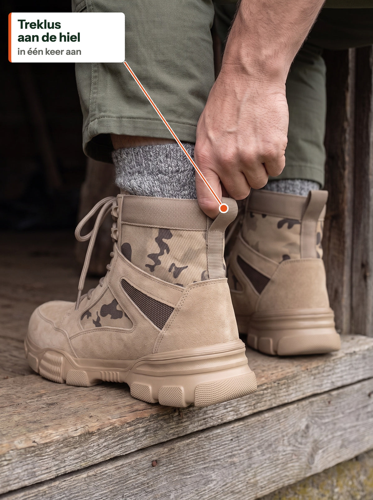 Hand trekt The Camo Work Boot aan via de treklus aan de hiel, op de drempel van een schuur (NL label)