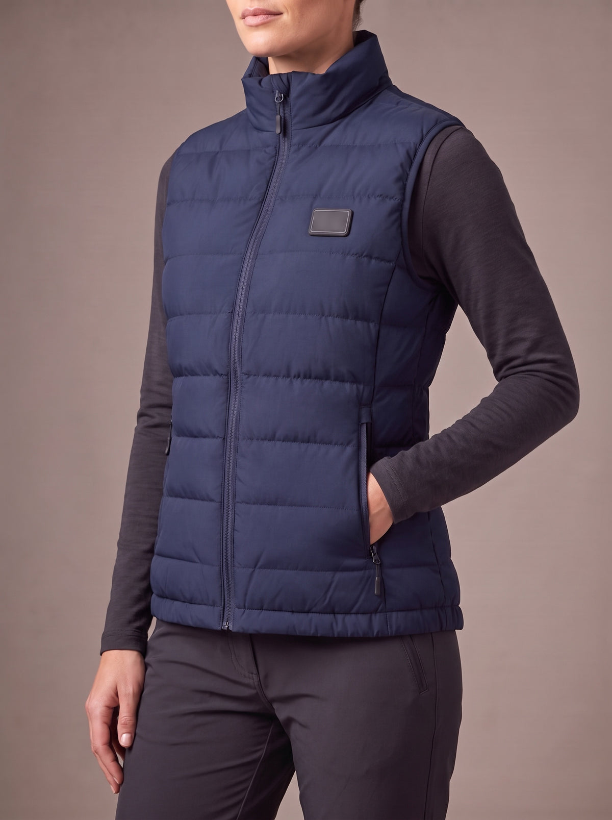 The HeatCore Bodywarmer Women in navy, studio, three-quarter view with a hand in the zipped pocket