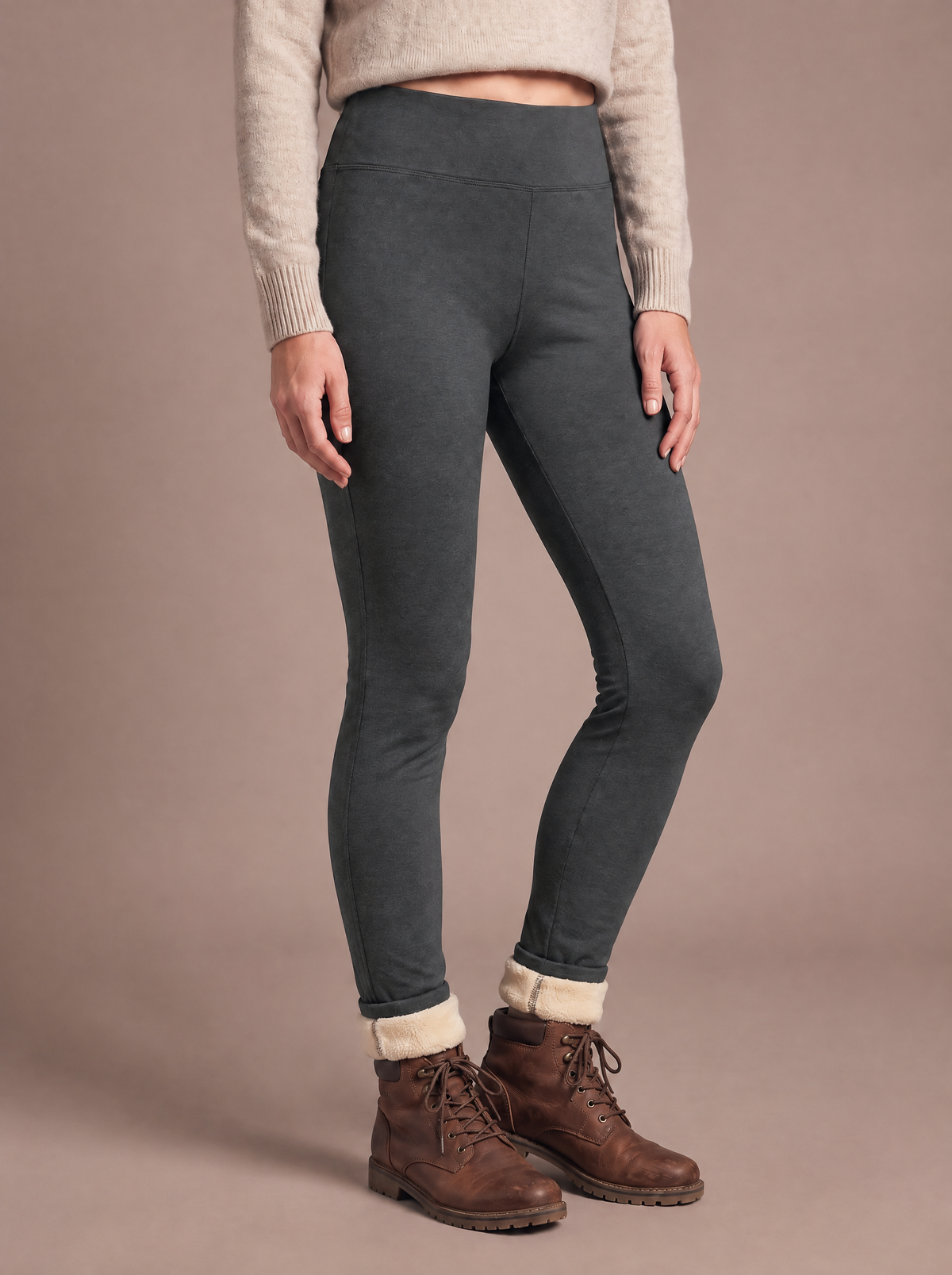 Woman wearing the high-waist sherpa-lined legging in dark grey, weight on one leg with a softly bent knee, cream lining at the turned-up ankles above brown walking boots