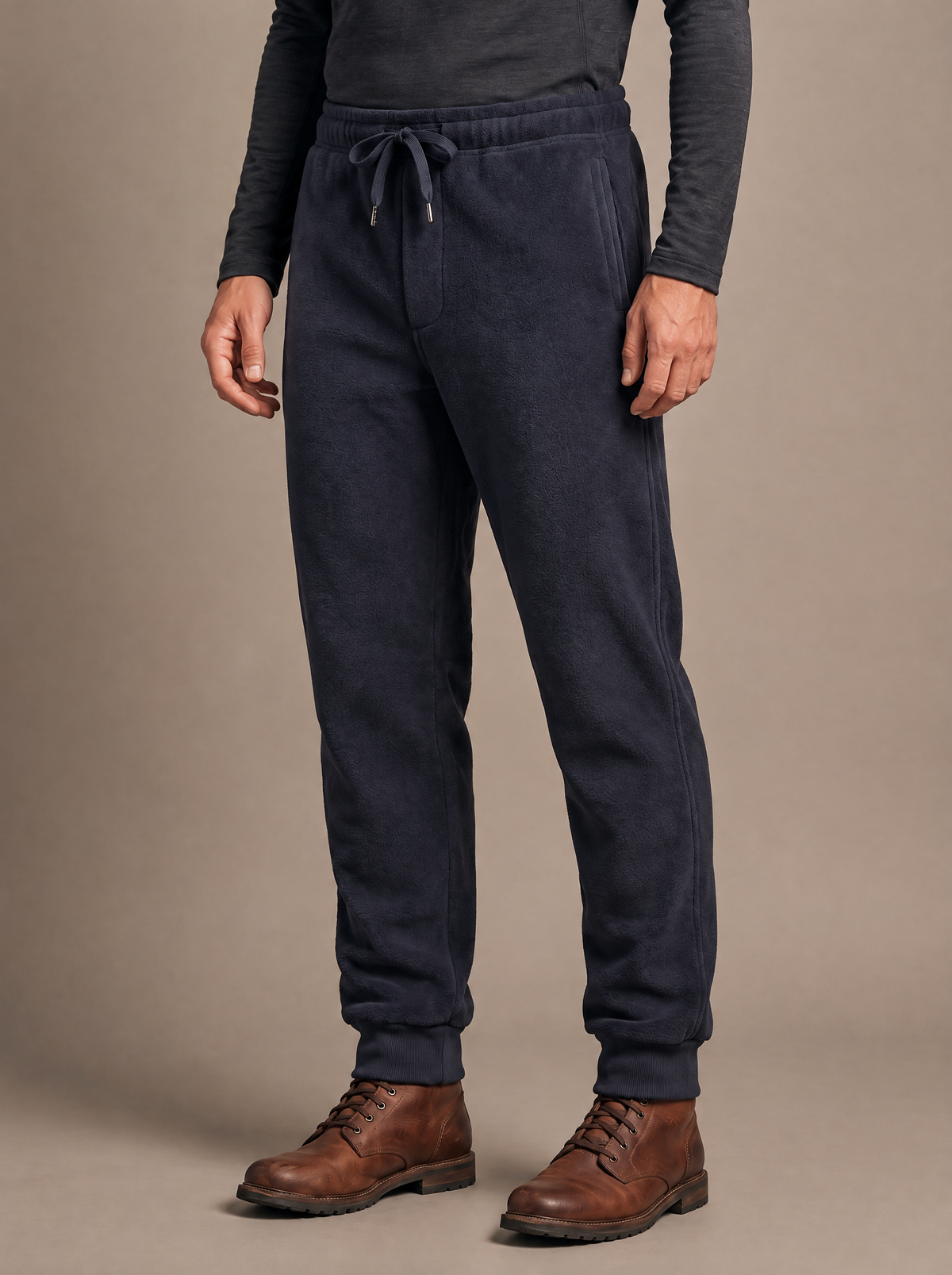 Double-face fleece jogger in navy worn from the waist down, body turned slightly with arms relaxed, drawcord waist and ribbed ankle cuffs