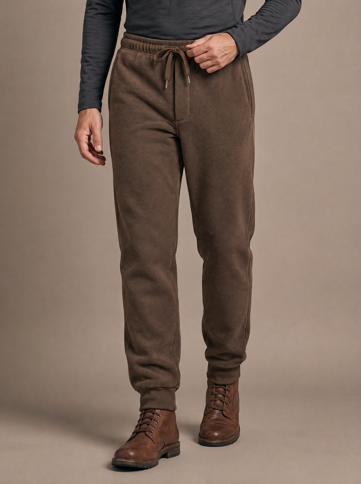 Double-face fleece jogger in coffee brown worn from the waist down, a half step forward with one hand at the drawcord, ribbed ankle cuffs