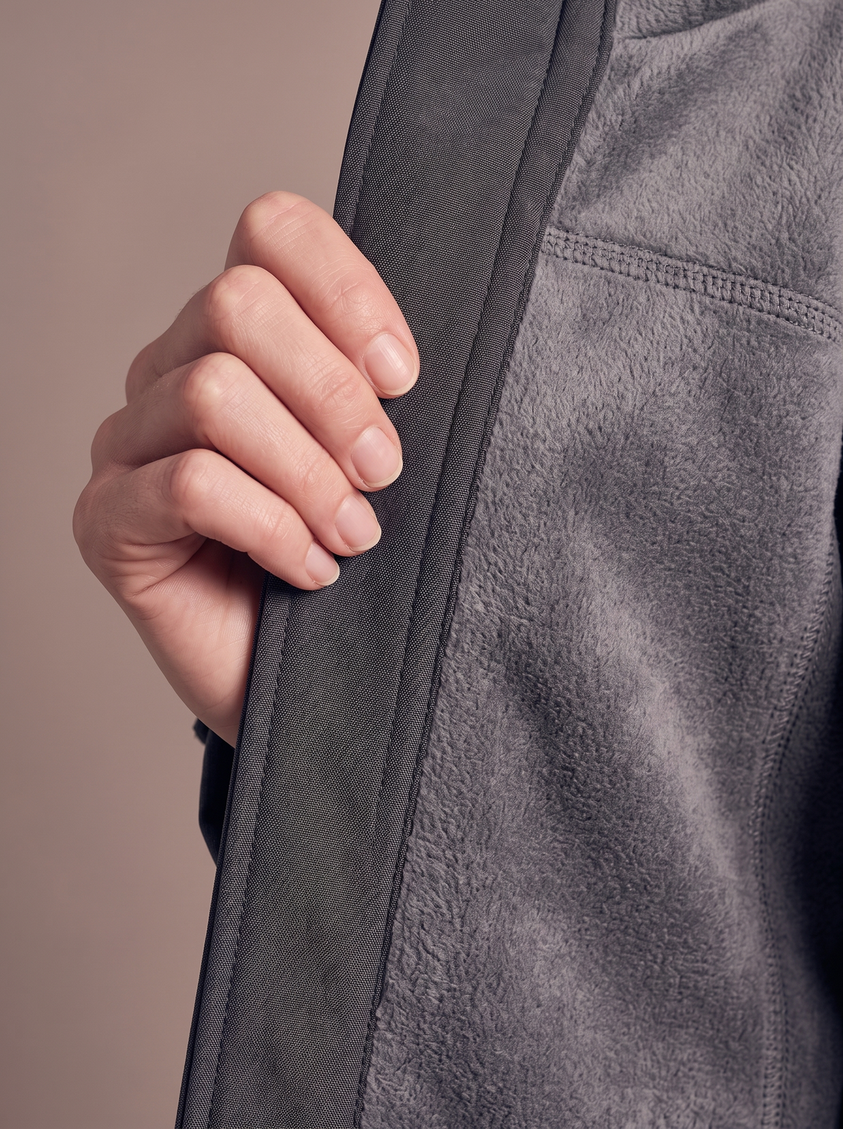Front edge of the charcoal softshell coat turned back by hand to show the soft grey brushed fleece lining behind the stretch shell