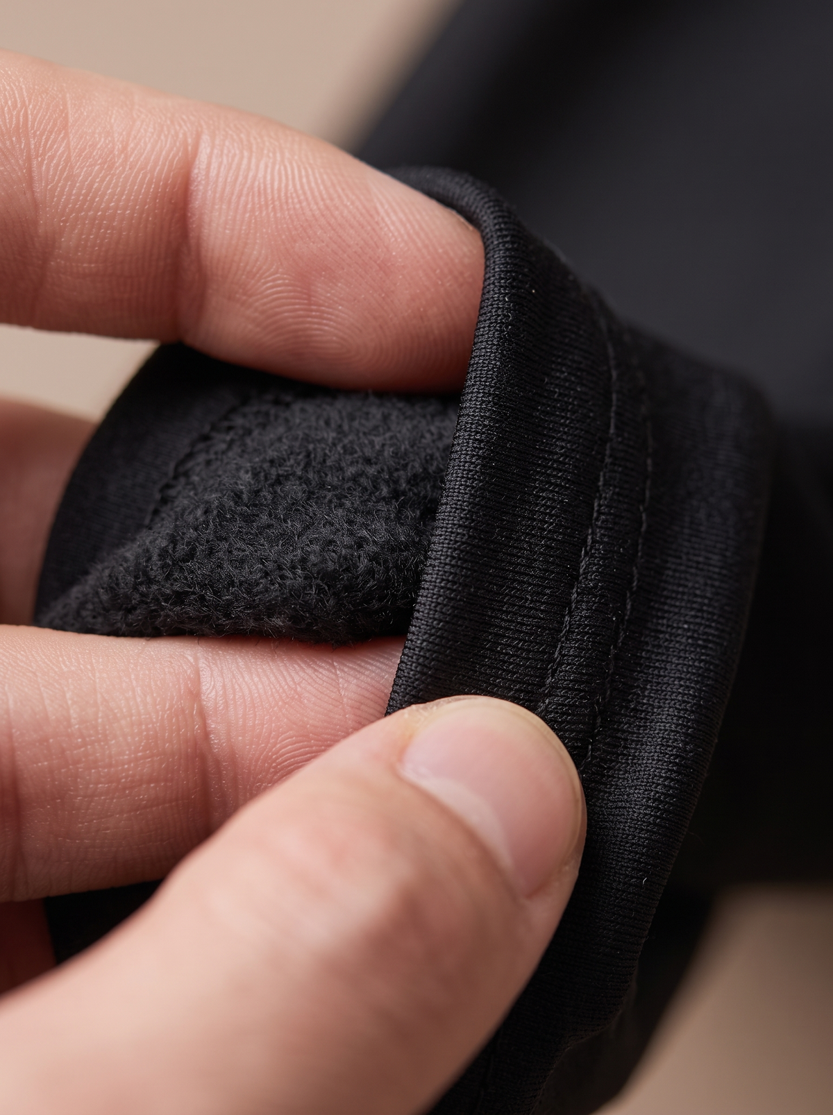 Close-up of the black thermal leggings turned back at the hem, showing the soft brushed inside next to the smooth outer face