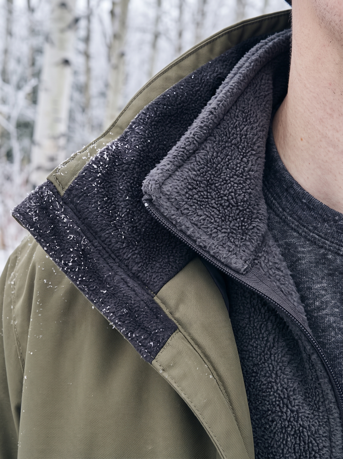 Frost on the collar of an olive fleece-lined shell worn open over a charcoal polar fleece and a brushed thermal knit base layer