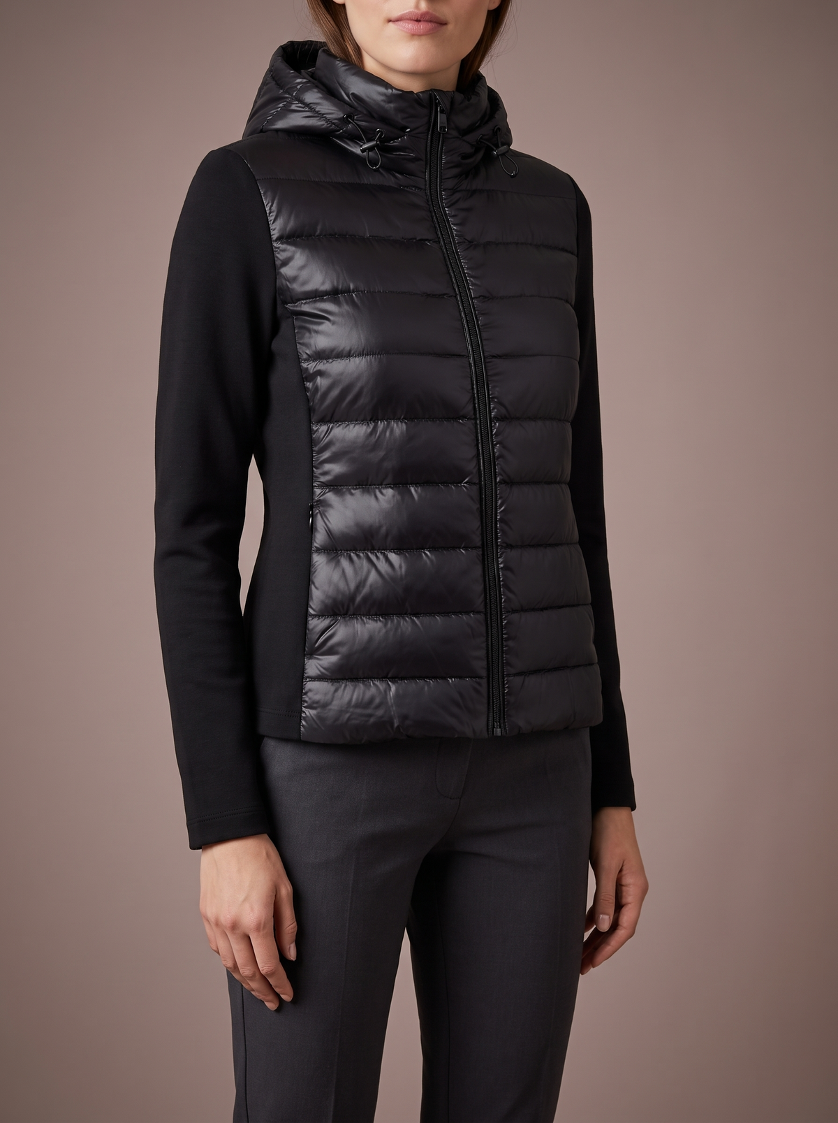 Women's black hybrid puffer jacket with quilted body and stretch sleeves, studio front view