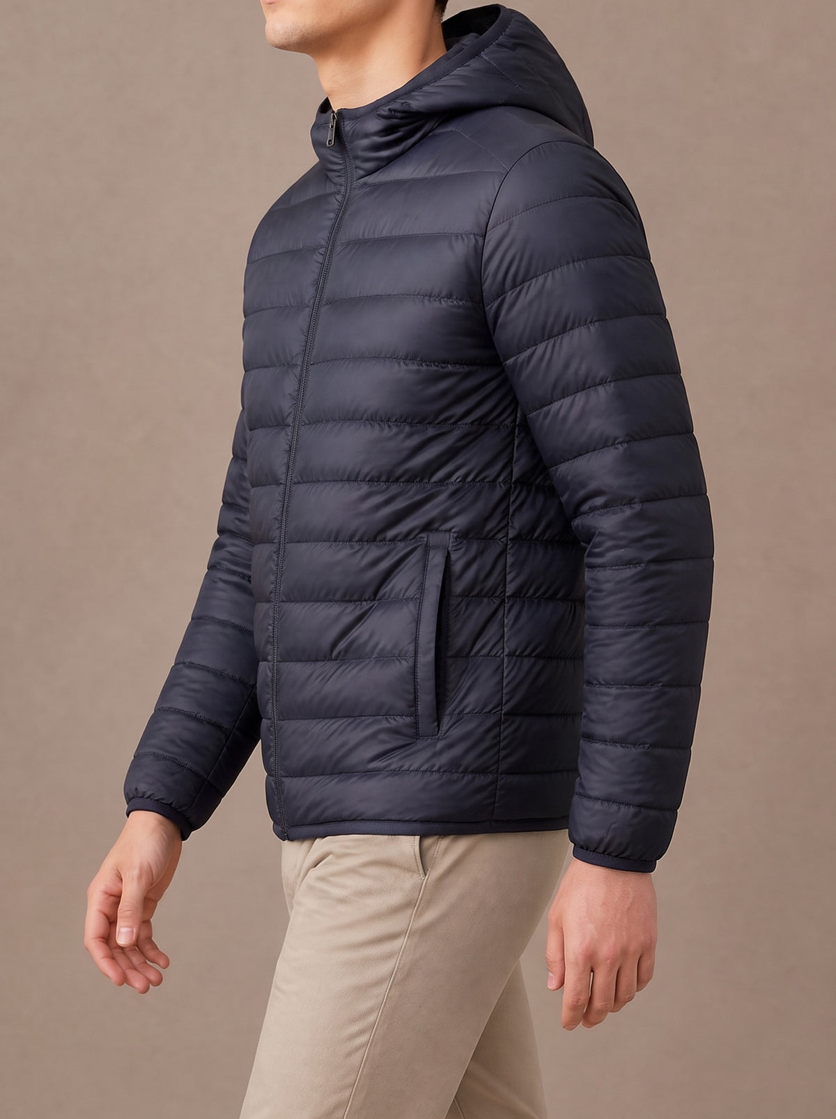 Navy packable down jacket from the side, walking, studio view