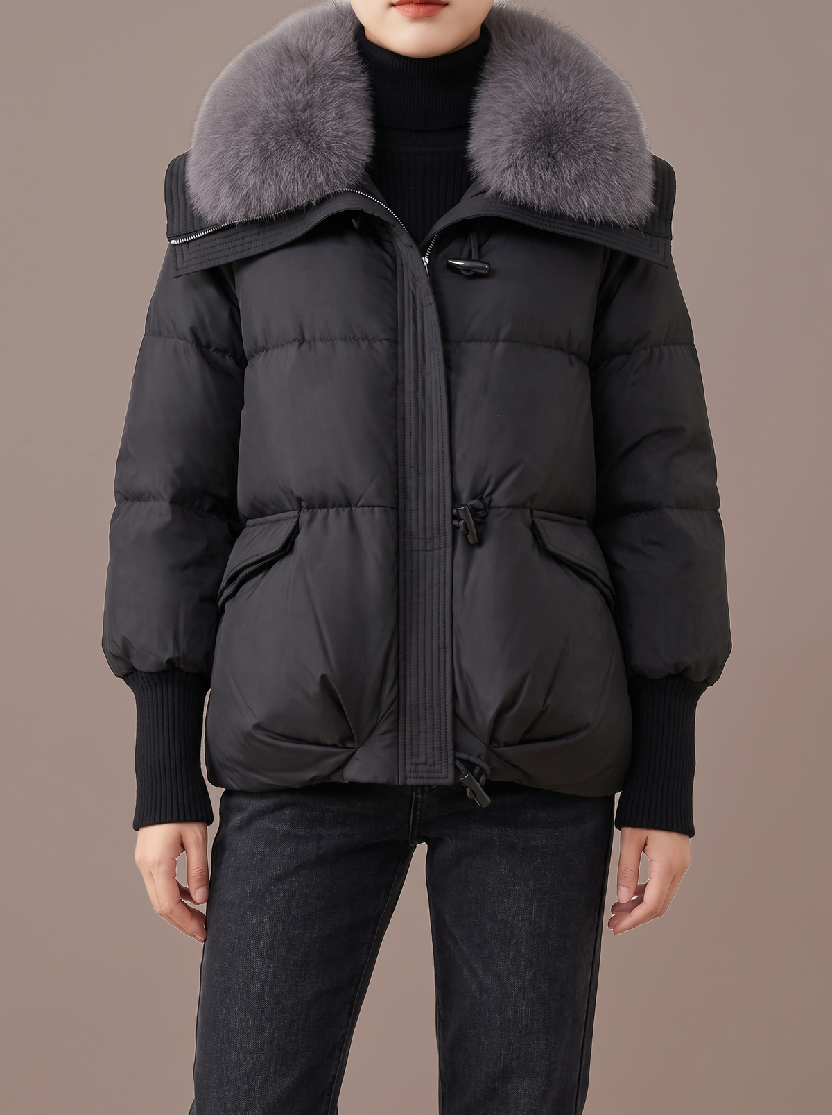 Women's black short padded jacket with a large grey plush collar, studio view