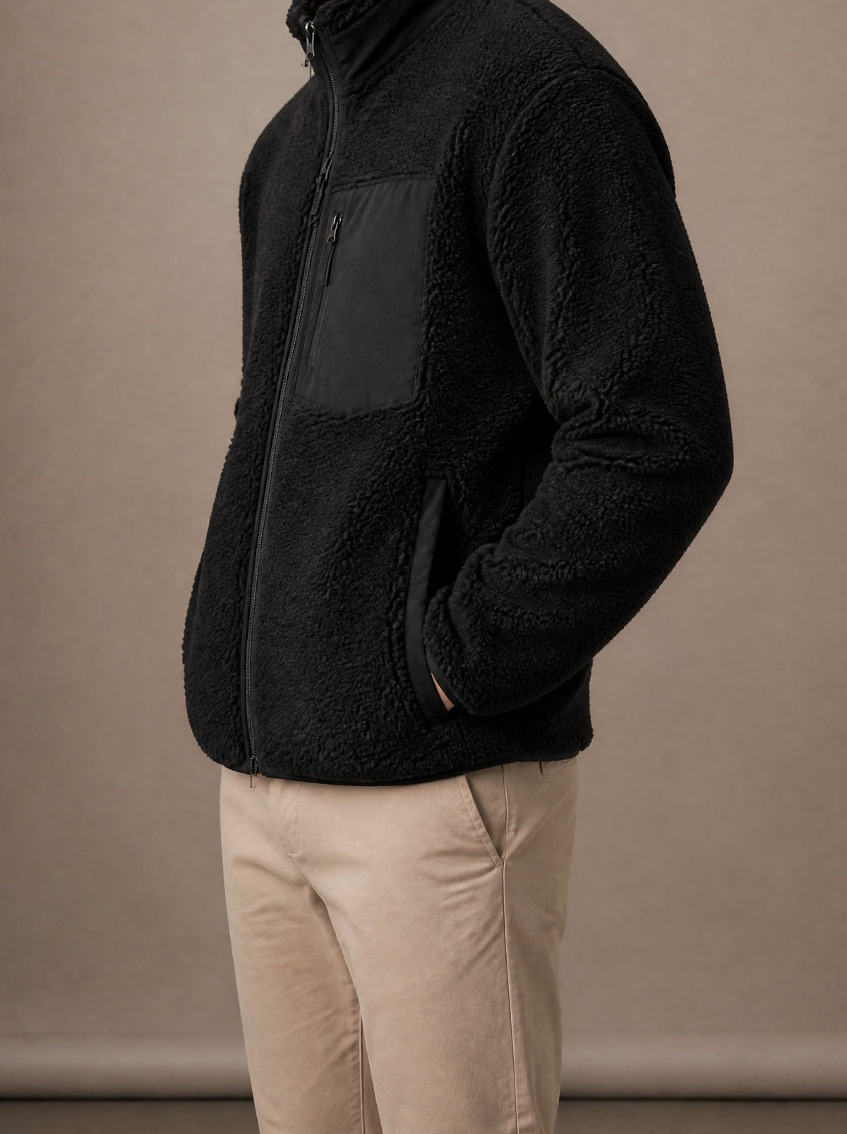 Black teddy fleece jacket from the side, hands in the pockets, studio view